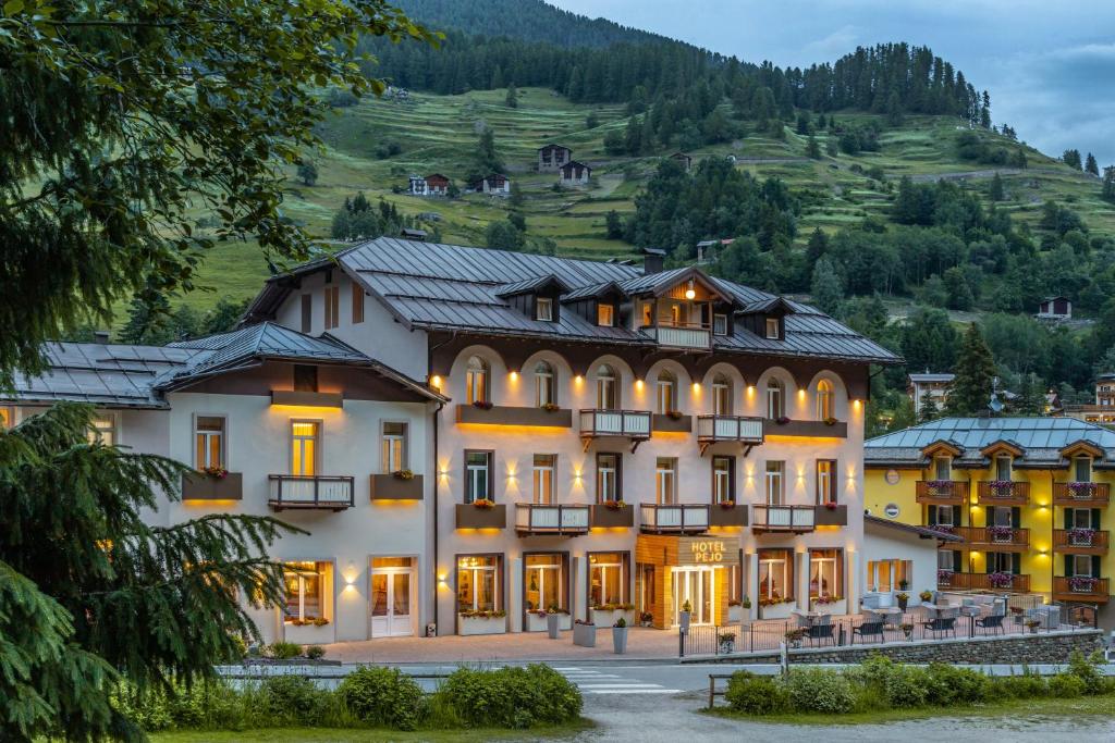 un grand bâtiment avec une montagne en arrière-plan dans l'établissement Hotel Pejo, à Peio Fonti