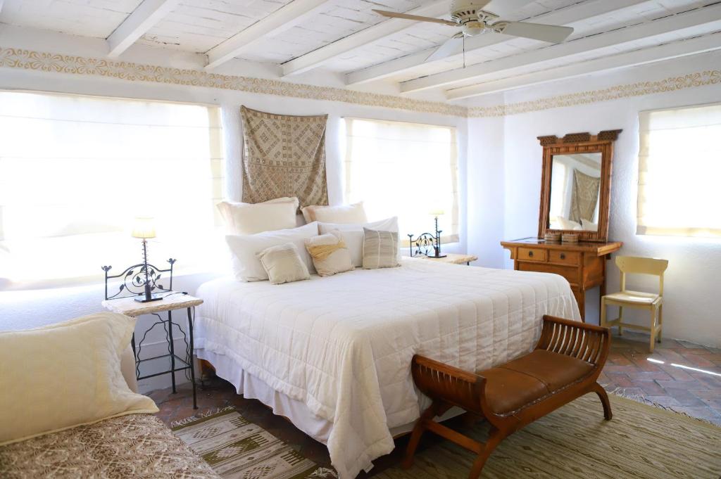 a bedroom with a white bed and a chair at Suites Santo Domingo in San Miguel de Allende