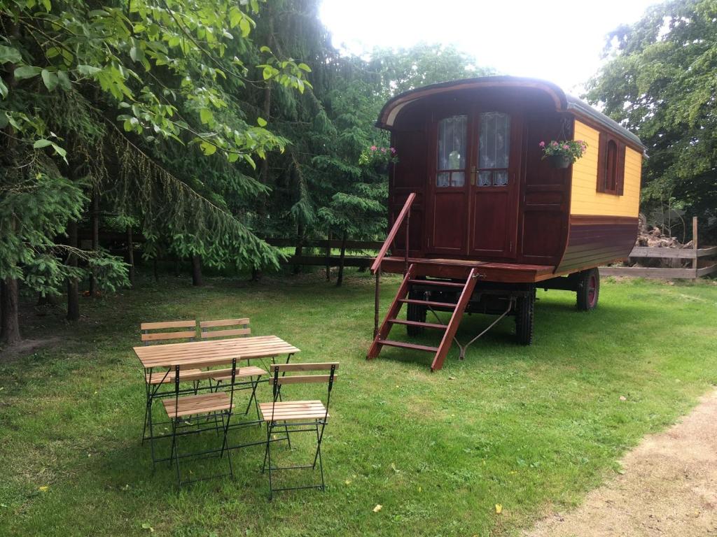 a rv parked in a field with a table and chairs at Domaine de Carnin in Beloeil
