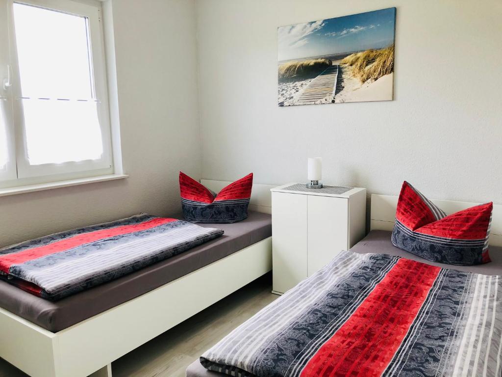 2 camas en un dormitorio con almohadas rojas en Apartments "Am Nationalpark", en Schwedt