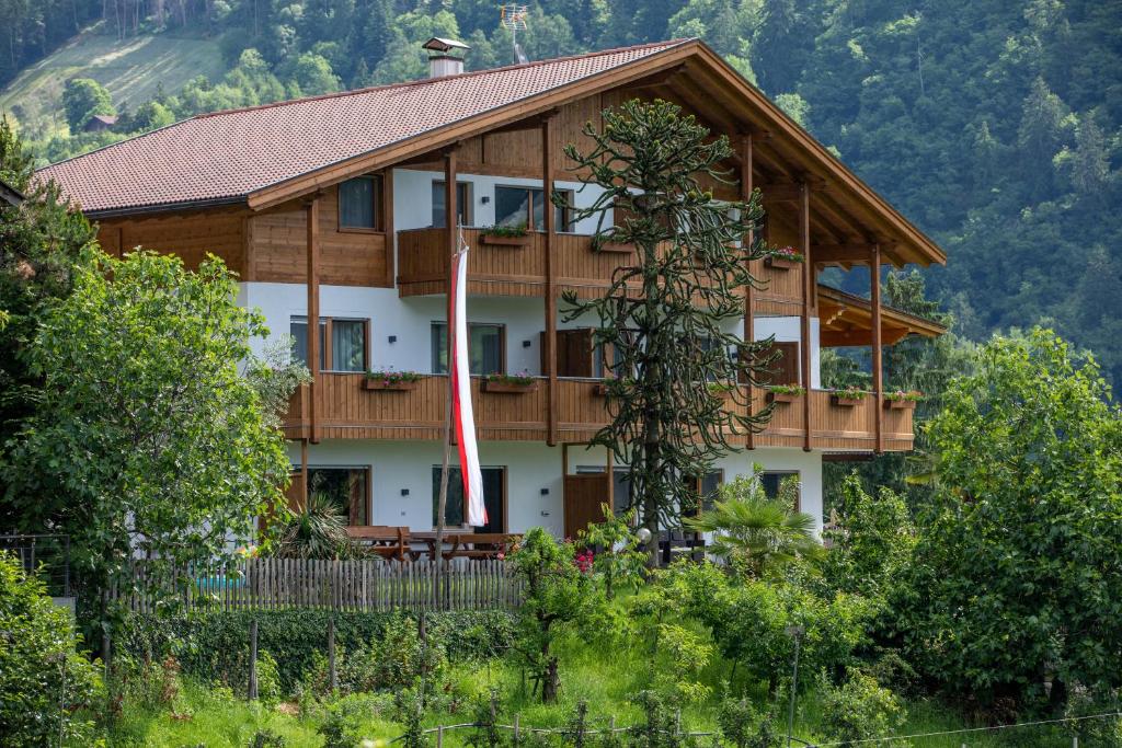 una grande casa in legno con un nastro rosso di Innermoarhof a Rifiano