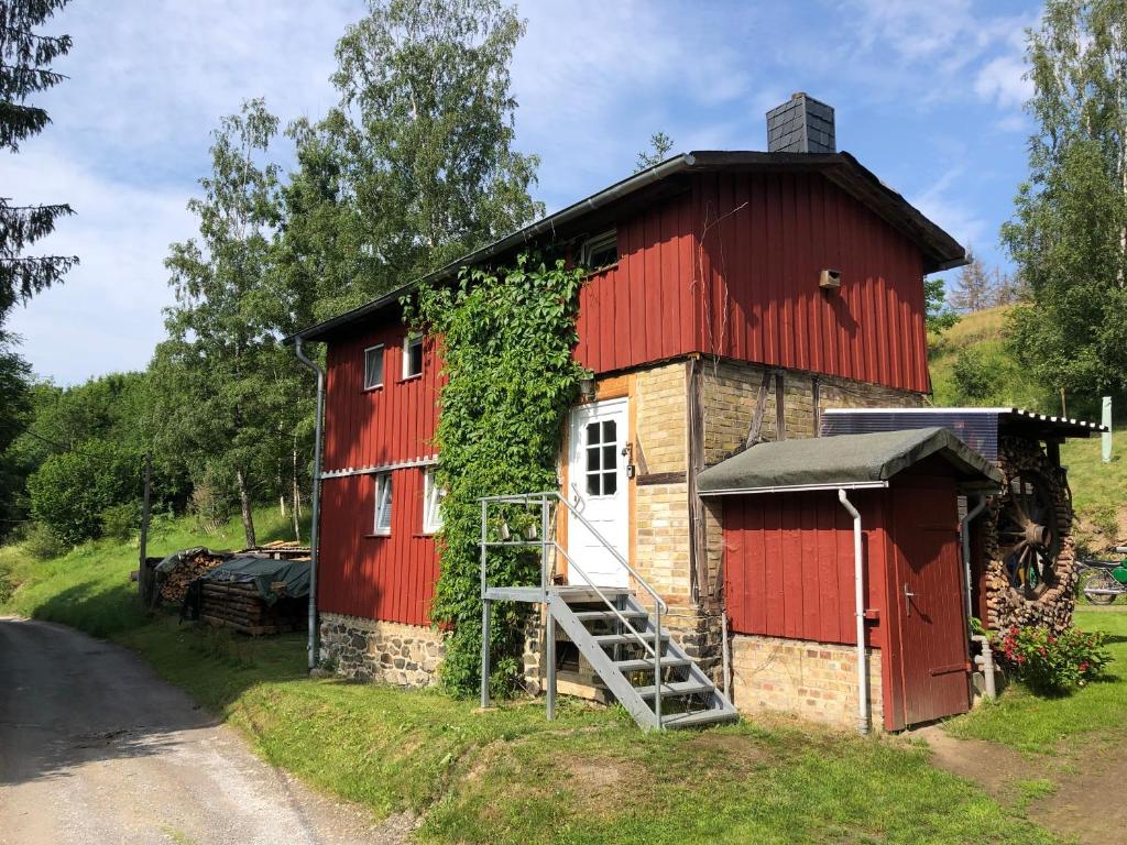 une grange rouge avec une porte rouge et une échelle dans l'établissement Ferienhaus am Hahnenkopf, à Rübeland