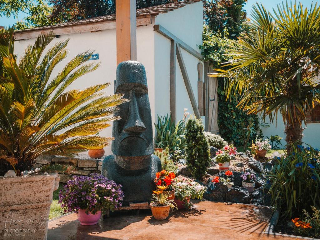 una estatua en un jardín con flores y plantas en Moai Home Apartman Sárvár en Sárvár