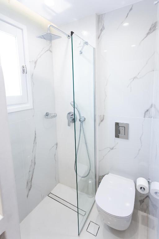a white bathroom with a shower and a toilet at Likio Studios in Batsi