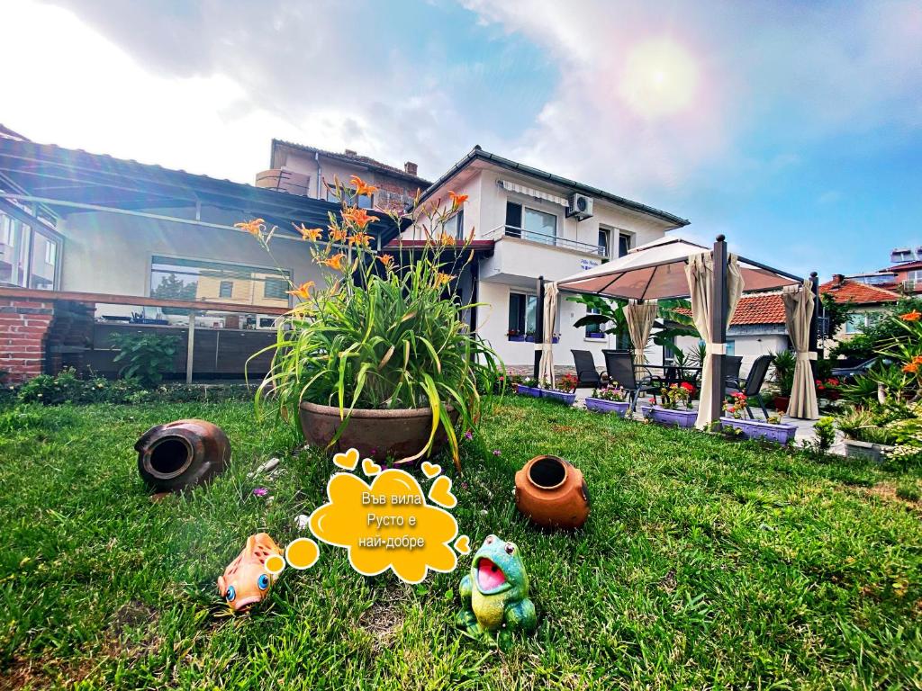 une cour avec une maison et quelques jouets dans l'herbe dans l'établissement Villa Rusto, à Kiten