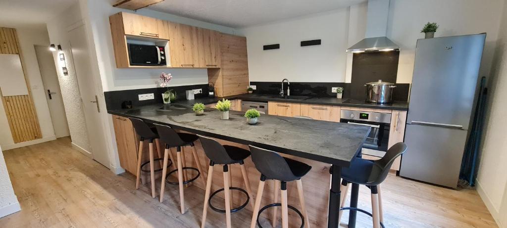 une cuisine avec un grand îlot et des tabourets de bar dans l'établissement Les Anémones, aux Orres