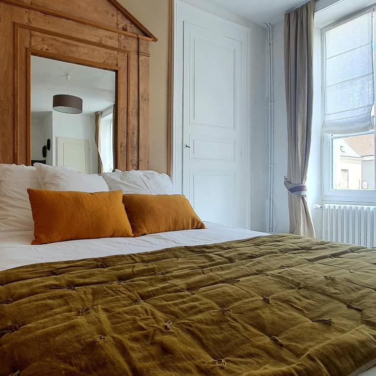 une chambre avec un grand lit avec un grand miroir dans l'établissement Aux Couleurs de Neuvy, à Neuvy-Saint-Sépulchre