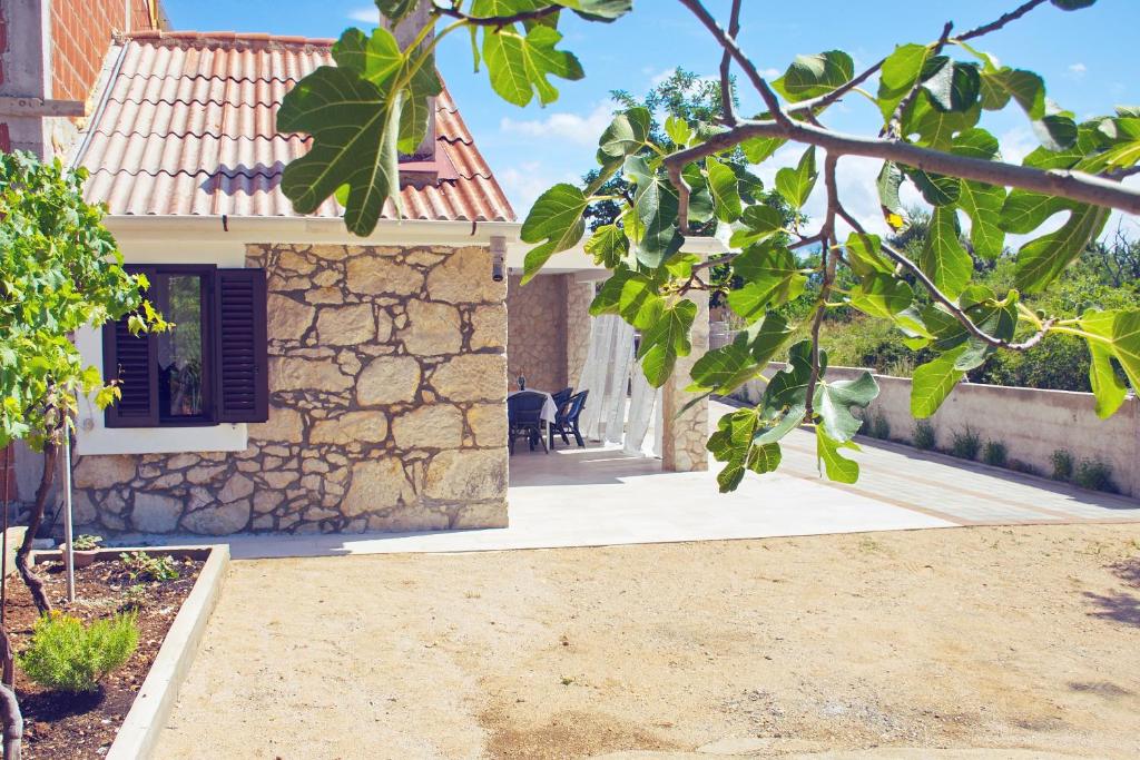 a house with a stone wall and a tree at Small Nature house Teodora in Novalja