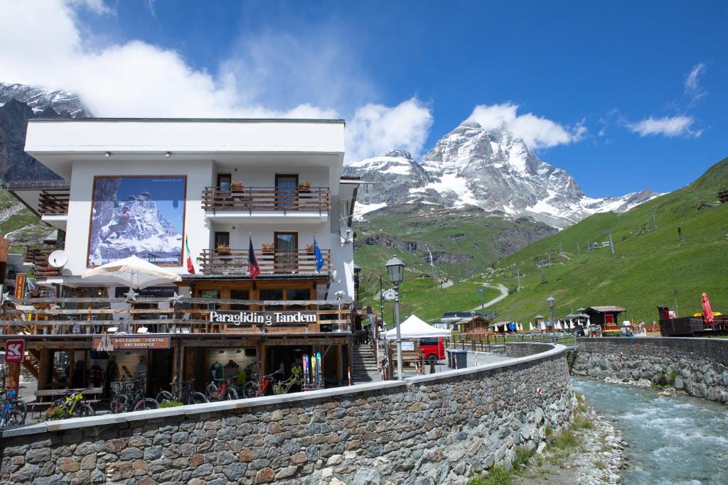 un edificio con un restaurante junto a un río y montañas en Hotel Meuble' Joli en Breuil-Cervinia