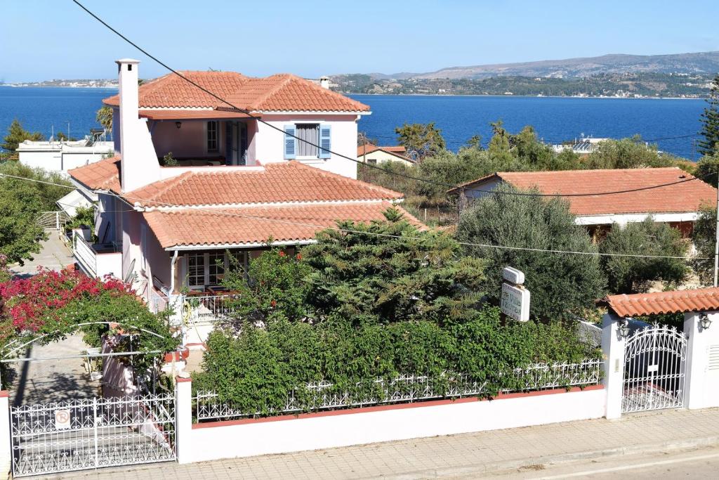 a house with a white fence in front of the water at Tzivras Villa & Apartments in Lassi