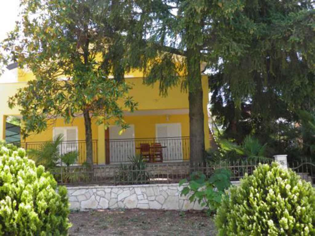 una casa amarilla con una valla delante de ella en Two-Bedroom Apartment in Porec V, en Poreč