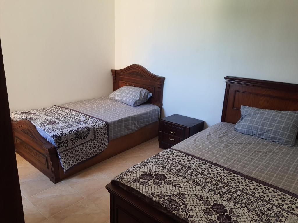 a bedroom with two beds and a night stand at Chalet first floor two bedrooms In Stella De Mare Ain El Sokhna For Families only in Ain Sokhna