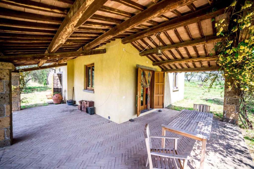 un patio con un banco de madera y un edificio en Holiday home in Tuscania VT/Latium 22377, en Tuscania