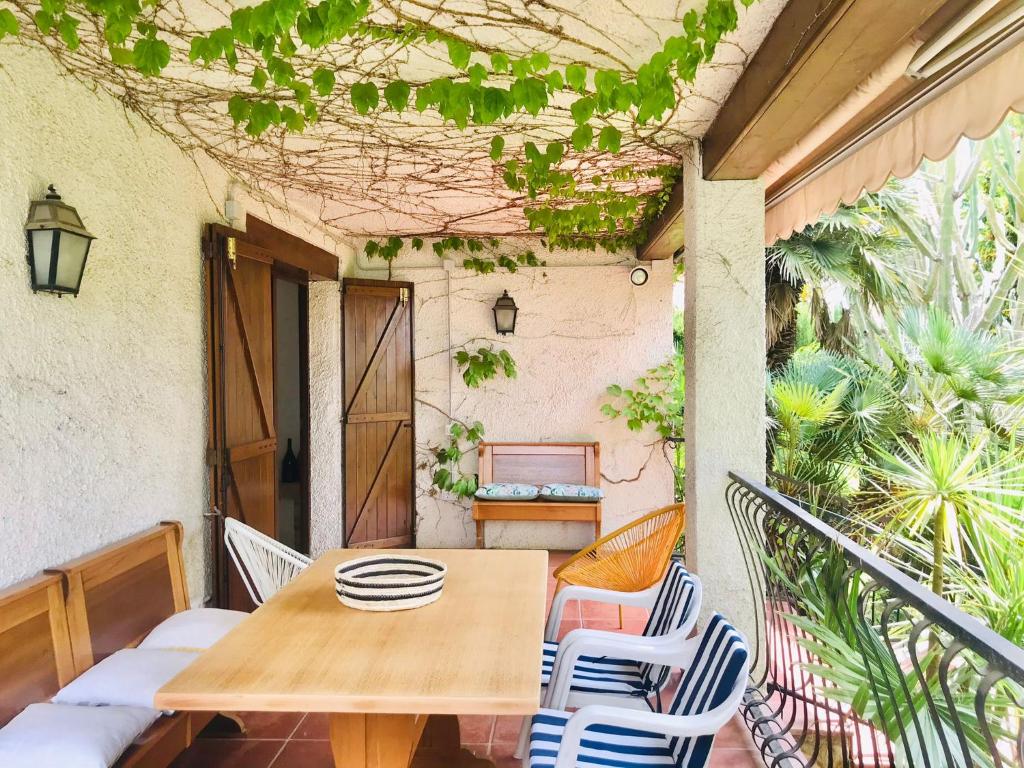a wooden table and chairs on a balcony with a table at Casa mediterránea con gran jardín y piscina a 500 m de la playa in Roda de Bará