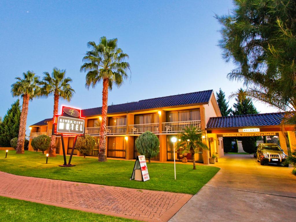 a house with palm trees in front of it at Mildura River City Motel in Mildura