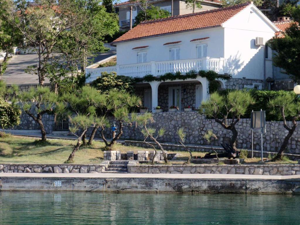 a white house next to a body of water at Apartment in Silo/Insel Krk 14603 in Šilo