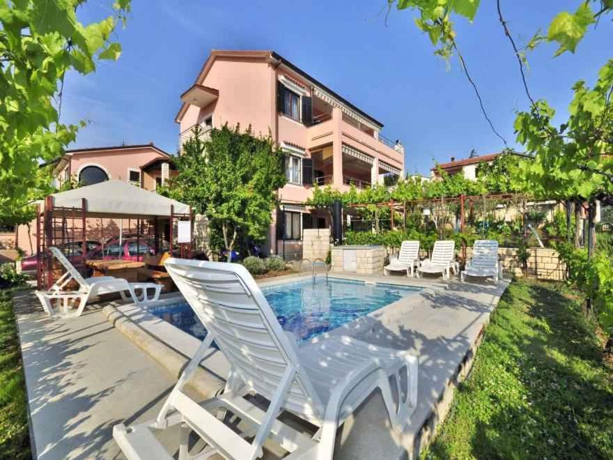 a house with a swimming pool with white lawn chairs at Apartment in Pula/Istrien 17385 in Veli Vrh