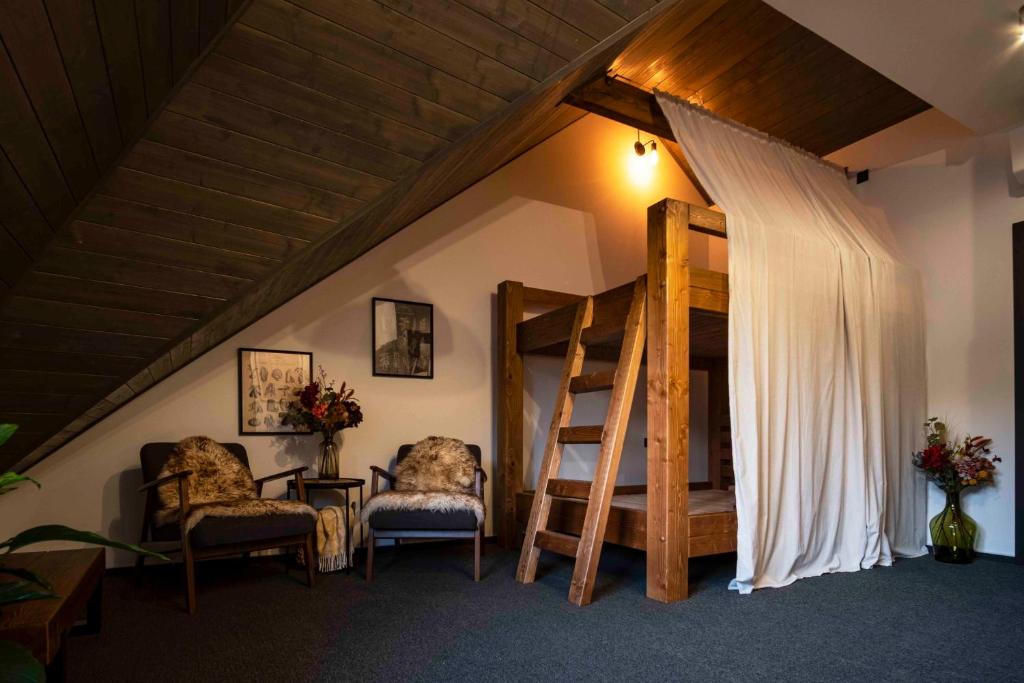 um quarto com uma cama alta, 2 cadeiras e uma mesa em Penzión u Sysľa em Muráň