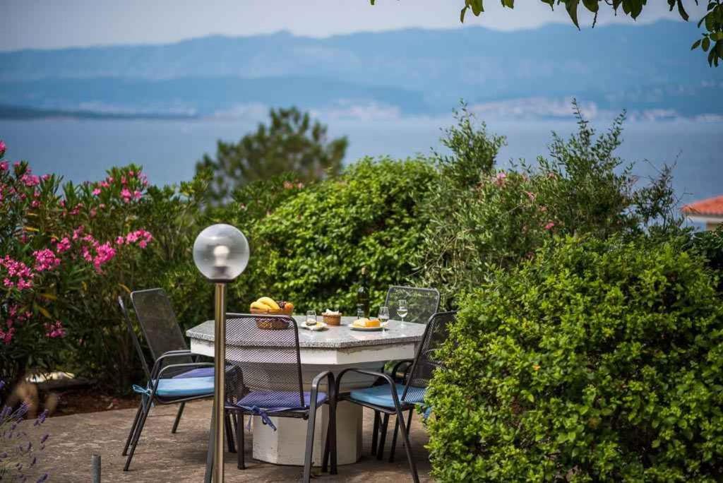 a table and chairs on a patio with a view of the ocean at Apartment Vrbnik 8 in Vrbnik