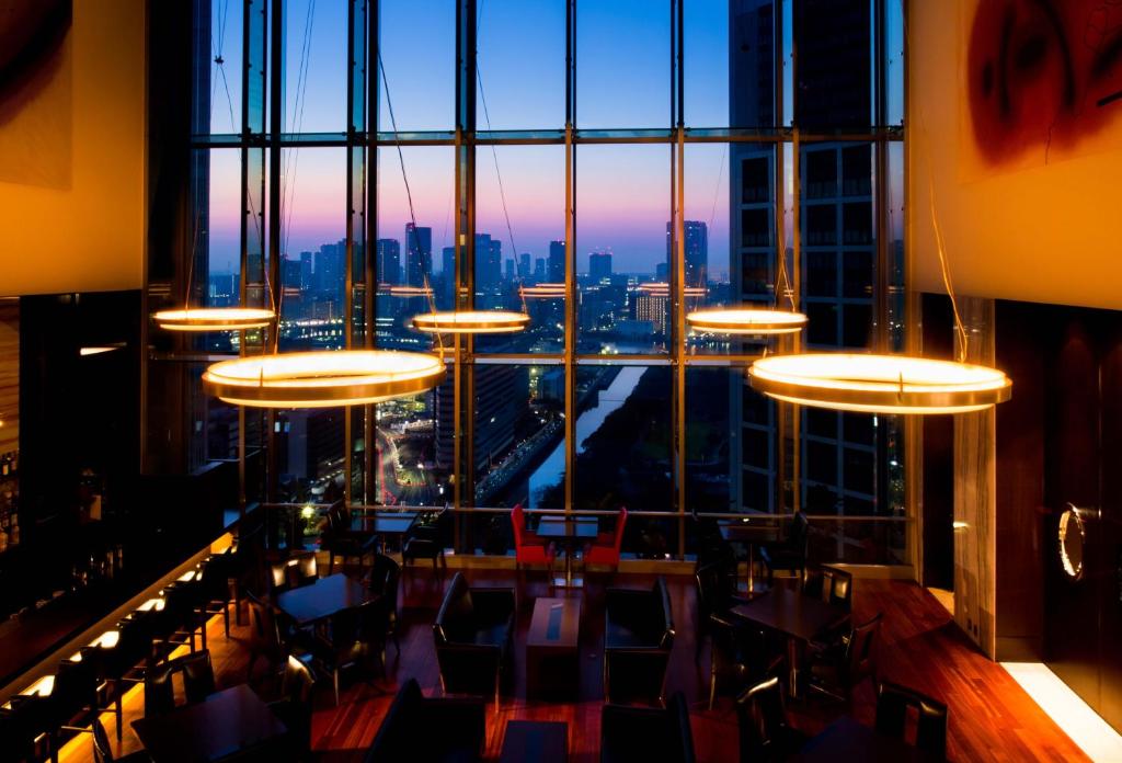 a dining room with a large window overlooking a city at The Royal Park Hotel Iconic Tokyo Shiodome in Tokyo