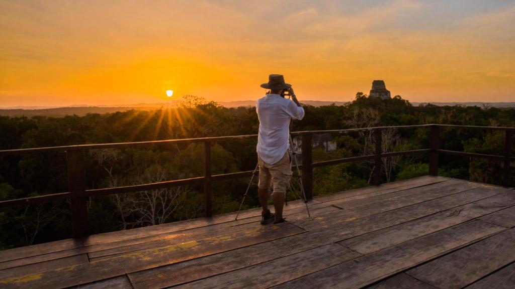 a man taking a picture of the sunset at the grand canyon at Hotel Jungle Lodge Tikal in Tikal