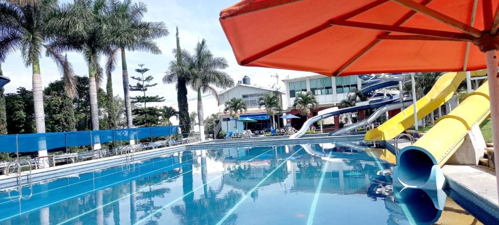 uma piscina com escorrega e um guarda-sol em Club Campestre El Eden em Yautepec
