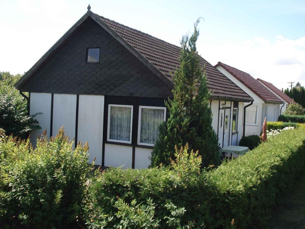 ein Haus mit einem schwarzen Dach und einer weißen Garage in der Unterkunft Holiday home Fuhlendorf 1 in Fuhlendorf