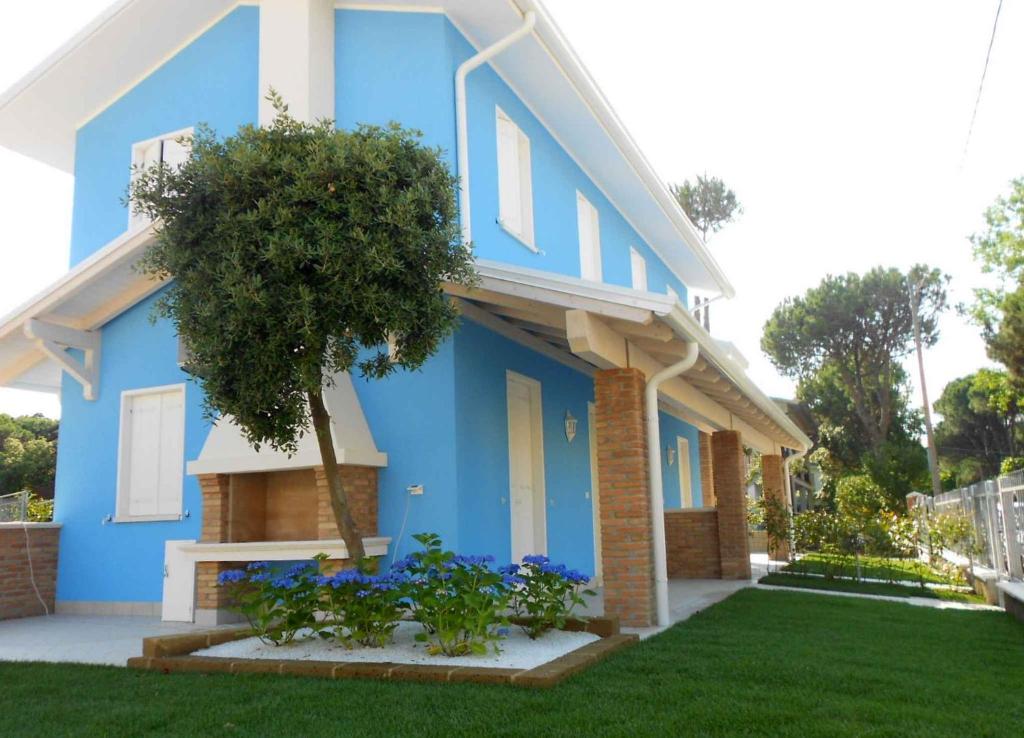 a blue house with a tree in the yard at Holiday Homes in Rosolina Mare 25014 in Rosolina Mare