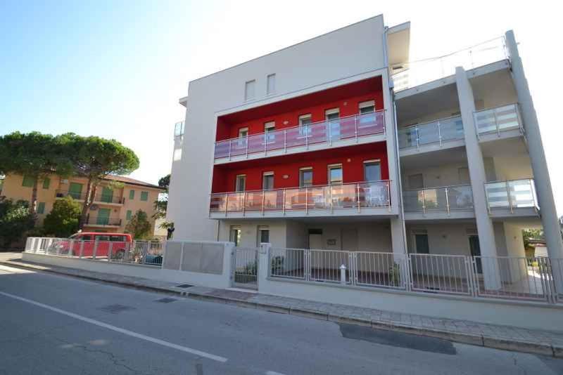 een wit en rood gebouw aan de straatkant bij Two-Bedroom Apartment Rosolina Mare near Sea 18 in Rosapineta