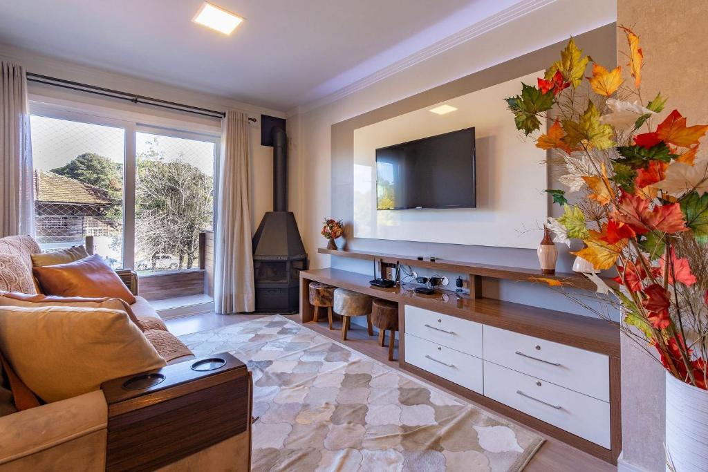 a living room with a couch and a television at 2 dorm Rua Coberta de Canela @stayhousetemporada in Canela
