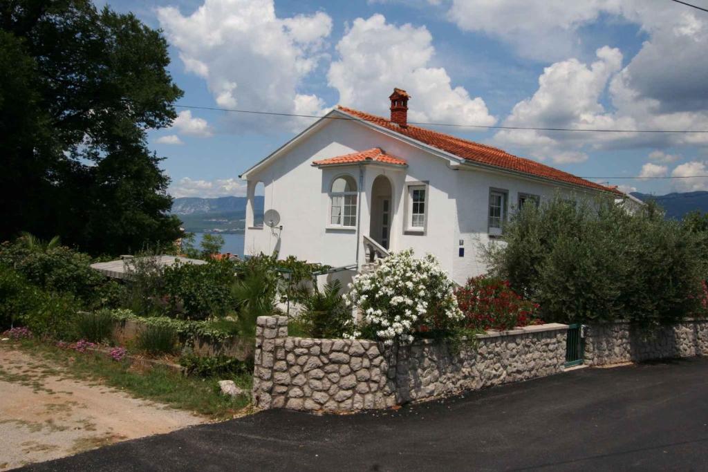 a small white house with a stone wall at Apartment Silo 36 in Šilo