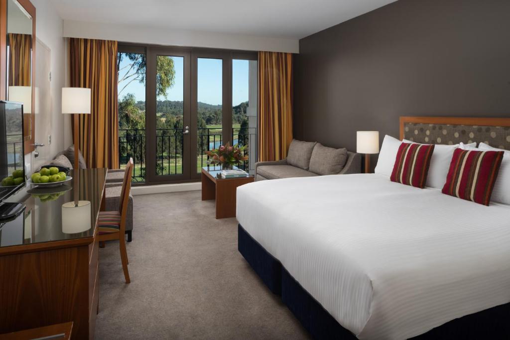 a bedroom with a large bed and a living room at Yarra Valley Lodge in Wonga Park