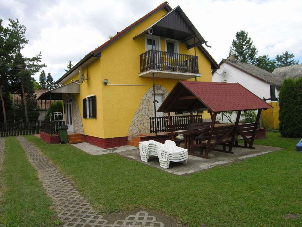 バラトンマーリアフュルドゥーにあるHoliday home in Balatonmariafürdo 19426の黄色の家(ピクニックテーブル、デッキ付)