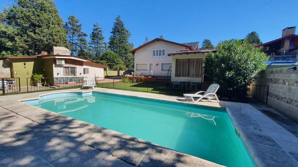 een zwembad met een stoel en een huis bij Teilen in Villa General Belgrano