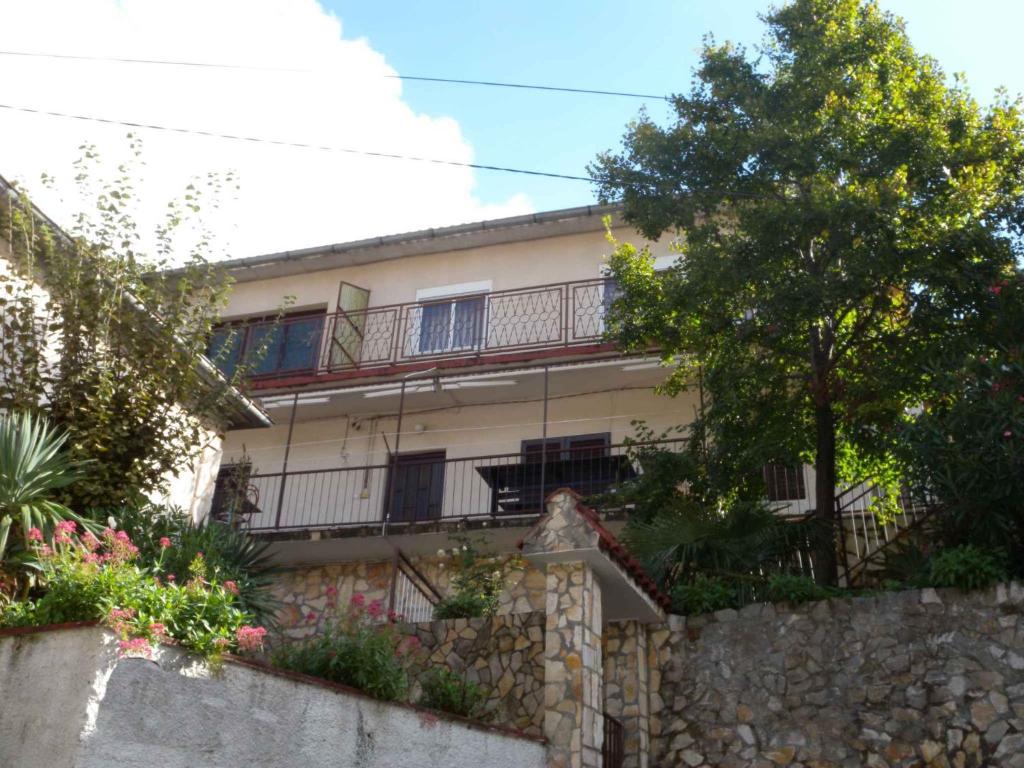 an apartment building with a stone wall and trees at Apartment Jablanac/Velebit Riviera 17115 in Jablanac