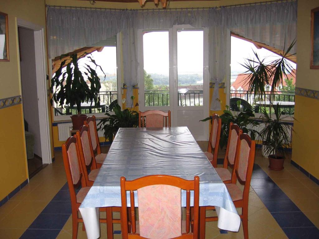 ein Esszimmer mit einem Tisch, Stühlen und Fenstern in der Unterkunft Apartment in Fonyod/Balaton 18594 in Fonyód