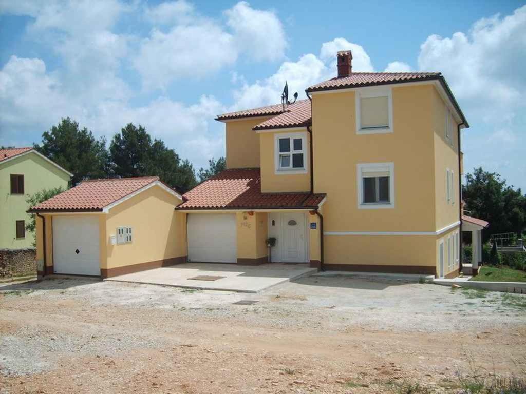 a large yellow house with two garage at Apartment Liznjan 5 in Ližnjan