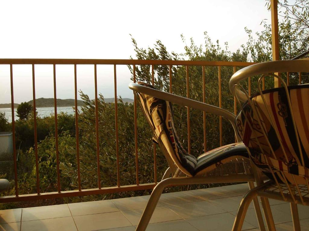 einen Stuhl auf einem Balkon mit Blick auf das Wasser in der Unterkunft Apartment Zlarin 1 in Zlarin