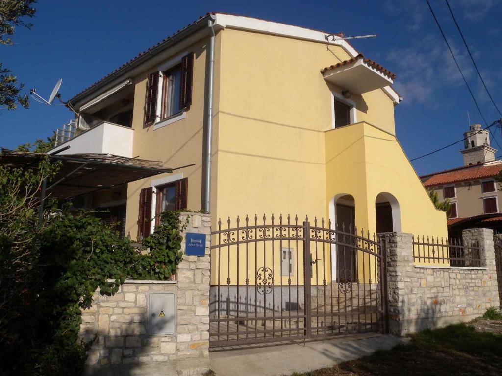 une maison jaune avec une clôture devant elle dans l'établissement Holiday home in Premantura/Istrien 10653, à Premantura