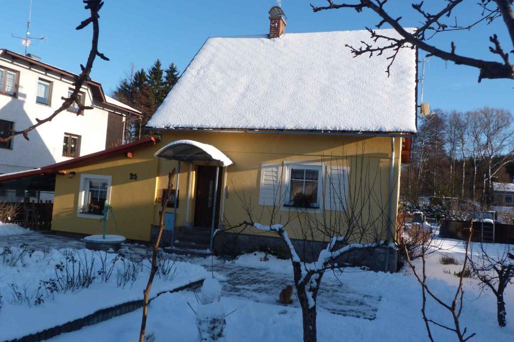 Holiday home Vrchlabi/Riesengebirge 2190 في Podhŭří: منزل أصفر صغير عليه ثلج