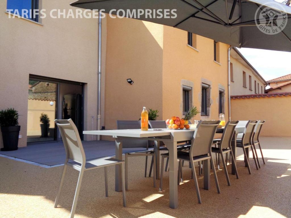 einem weißen Tisch mit Stühlen und einem Regenschirm vor einem Gebäude in der Unterkunft Gîte Montchal, 6 pièces, 12 personnes - FR-1-496-234 in Montchal