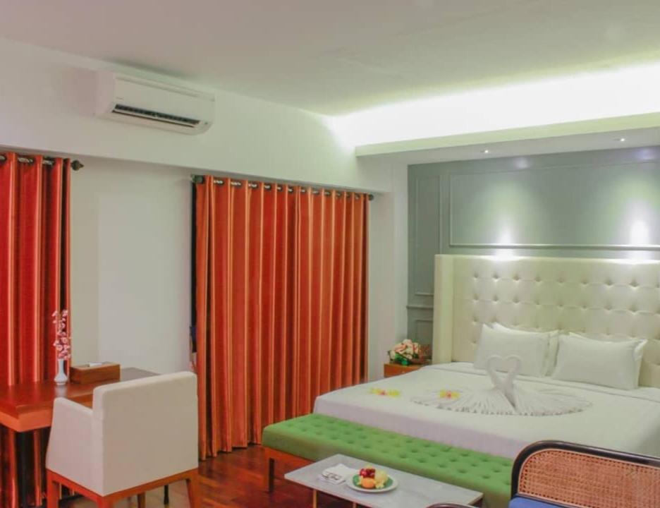 a bedroom with a large bed and a table and a desk at Kyriad Arra Hotel Cepu in Cepu