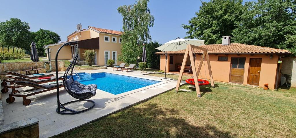 een achtertuin met een zwembad met een schommel en een huis bij Sunny Garden Villa with Pool in Loborika