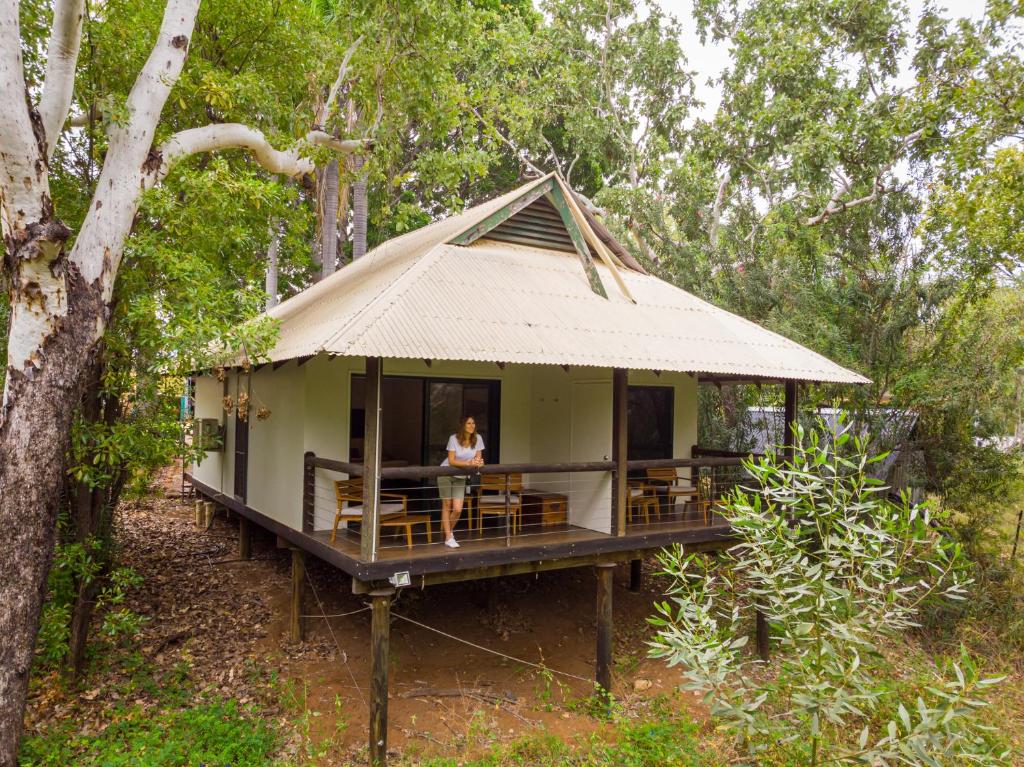 a woman sitting on the porch of a house in the forest at The Station at El Questro in Kununurra