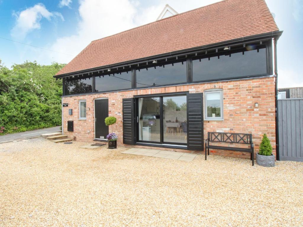 a brick house with large glass windows and a bench at Meadow View Barn in Wareham