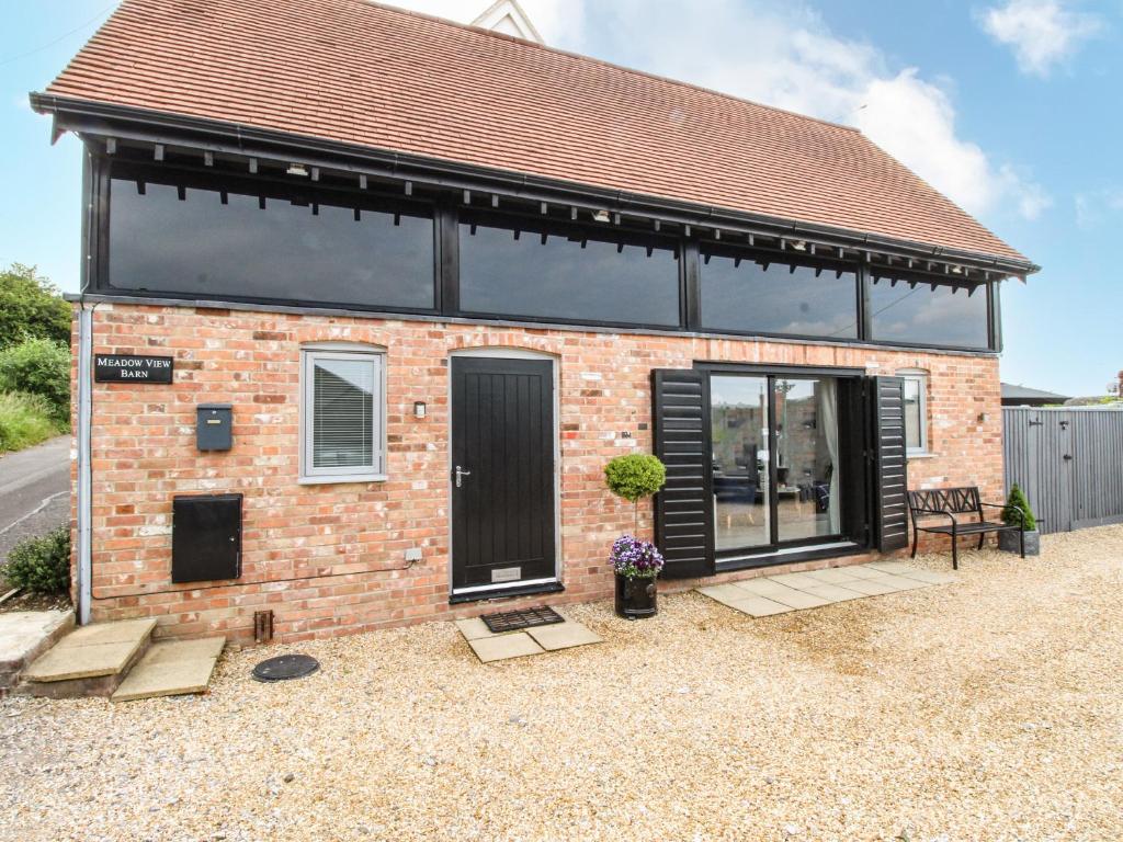 a small brick house with a large window at Meadow View Barn in Wareham