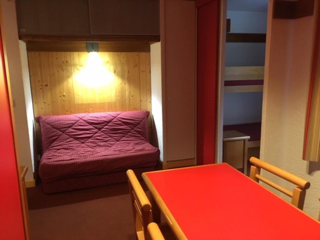 Plagne 1800にあるAppartement Plagne 1800, 2 pièces, 4 personnes - FR-1-351-92の赤いテーブルとベッドが備わる小さな客室です。