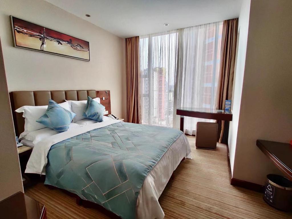 a bedroom with a bed with blue pillows and a window at L Hotels Changsheng Branch in Zhuhai