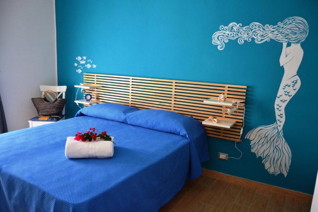 a bedroom with a blue bed with a flower arrangement on it at B&B Vivere il Mare in San Vito lo Capo