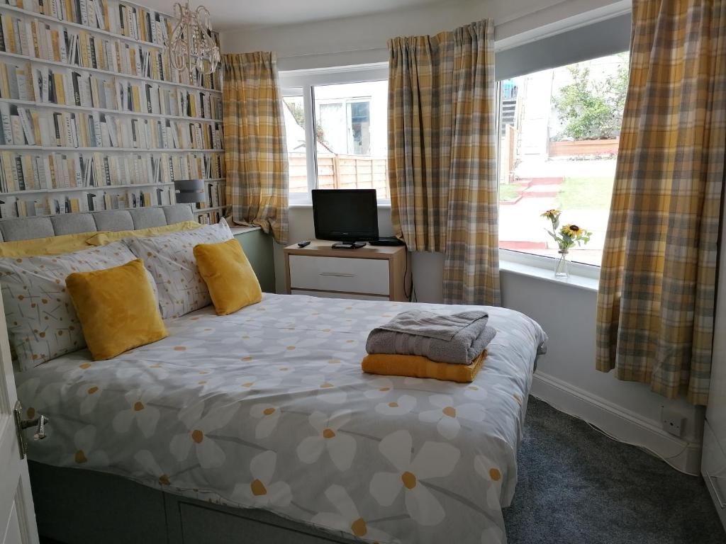 a bedroom with a bed with yellow pillows and a window at Stunning holiday accommodation by the sea in Paignton